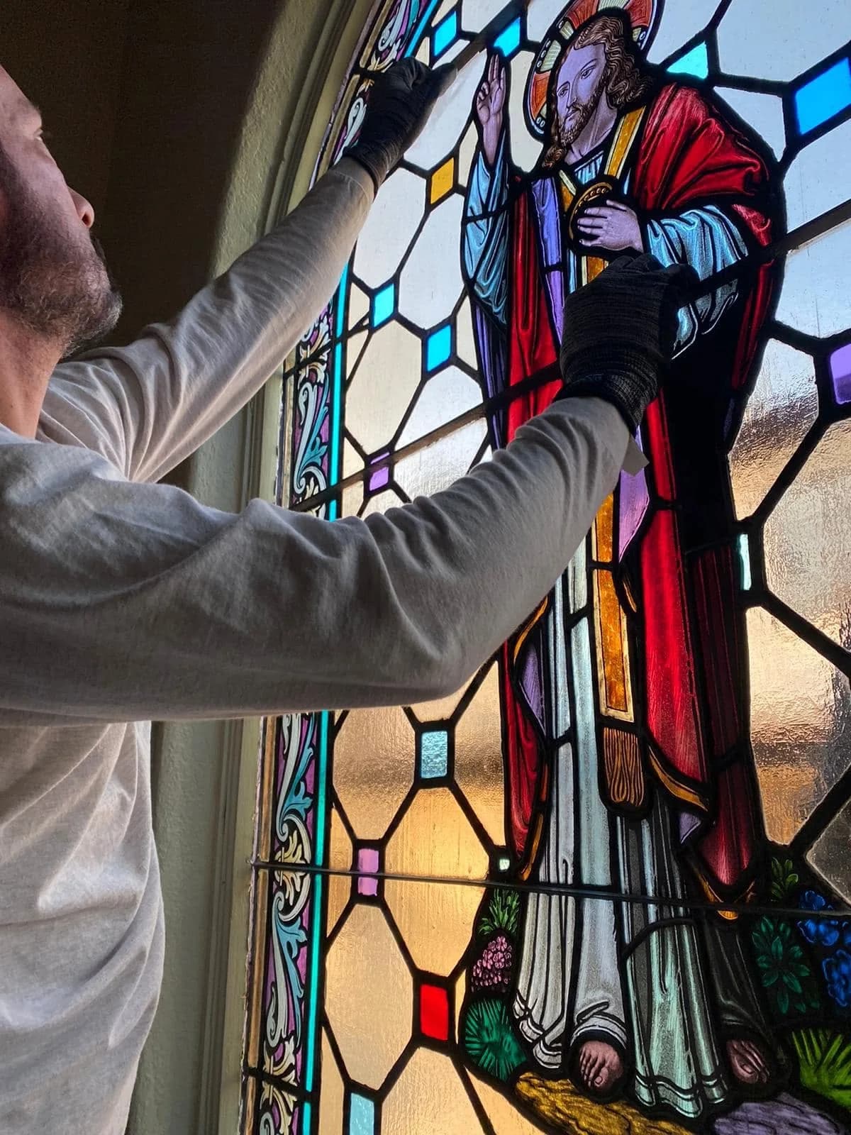 Craftsman repairing a religious stained glass window with detailed leadwork